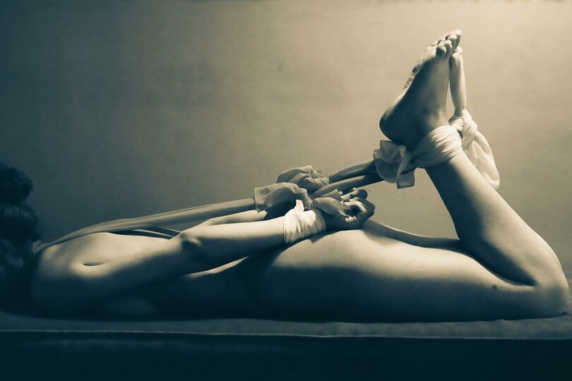 Femme allongé sur le ventre attaché avec un linge par les pieds et mains bondage avec corde