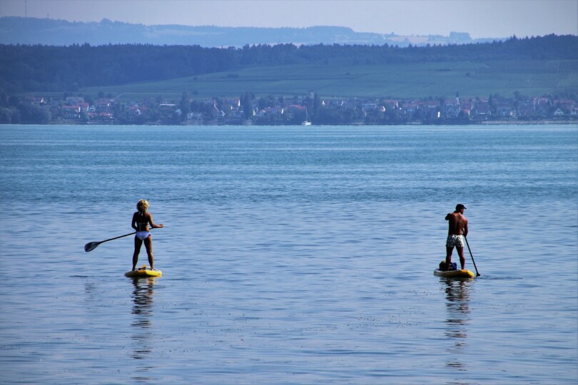 Moment sportif en duo : un homme et une femme sur l’eau avec des paddles