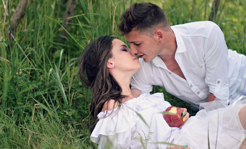 Un homme et une femme allongé dans l’herbe qui savent comment bien embrasser