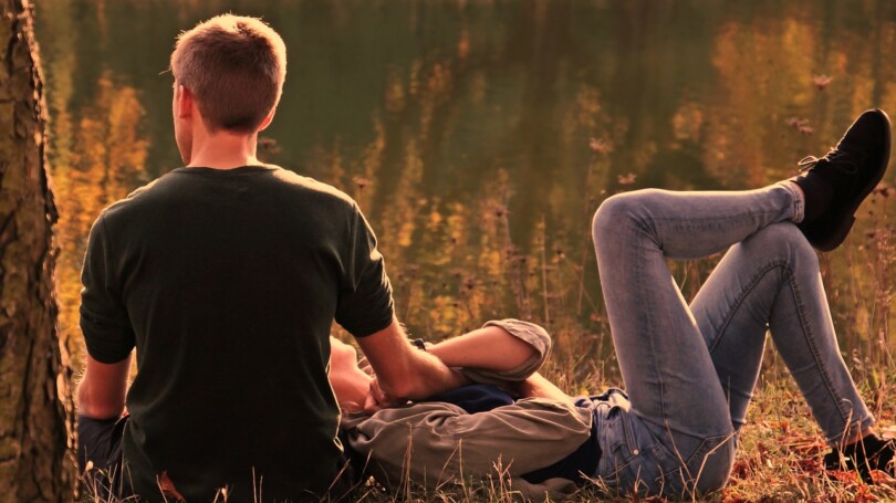 Un homme et une femme allongé dans l'herbe se tenant pas les mains