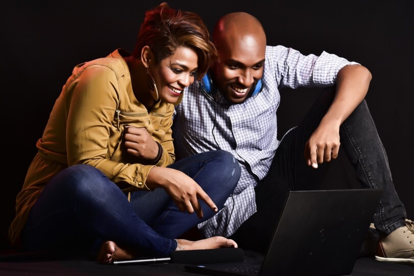 Un homme et une femme assis souriant devant un ordinateur