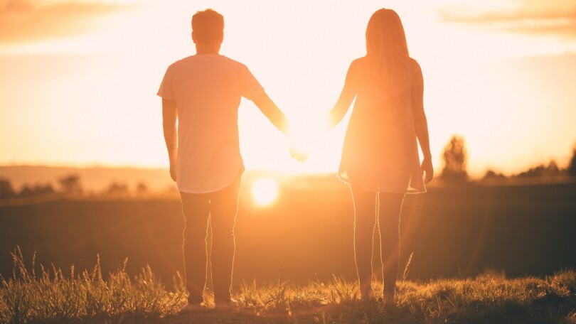 Un homme et une femme de dos qui regarde un coucher de soleil