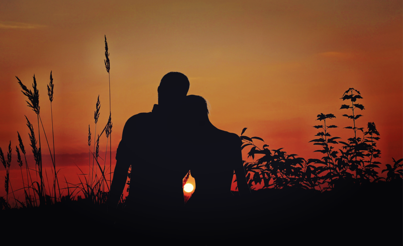 Un homme et une femme qui regarde un coucher de soleil