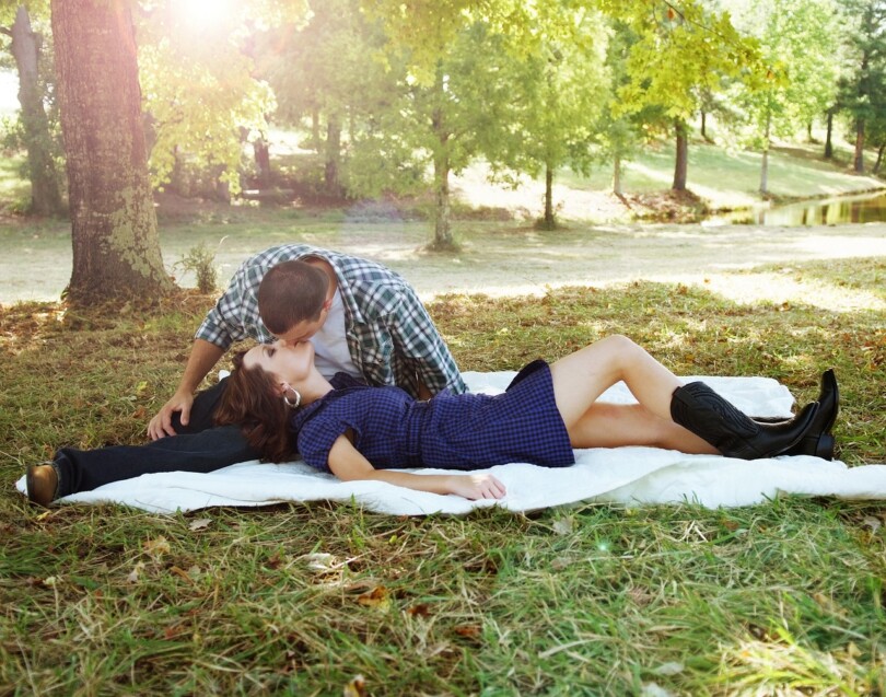 Un homme français qui embrasse son amoureuse dans un parc au sol