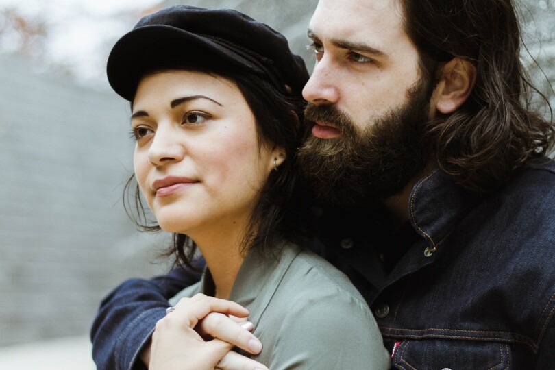 Un homme qui tien une femme femme de dos contre son corps et qui regarde au loin