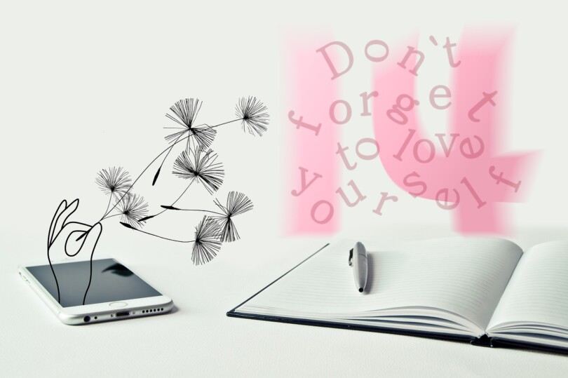 Un tableau intimiste capture l'essence de l'amour de soi : un téléphone affiche une application de rencontres en ligne, reposant à côté d'un cahier avec le doux rappel, "n'oublie pas de t'aimer
