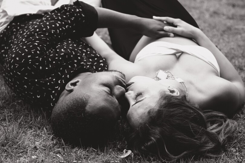 Une femme et un homme allongé au sol qui s’embrasse tout en se touchant mutuellement leur corps
