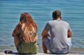 Une femme et un homme assis de dos face a la mer qui ne se parle pas