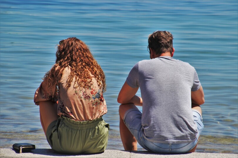 Une femme et un homme assis de dos face a la mer qui ne se parle pas