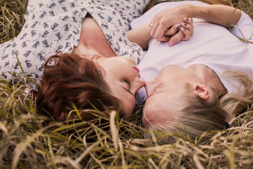 Une femme et un homme infidèle qui s’embrasse en toutes discrétion dans l’herbe