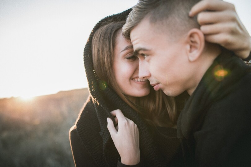 Une femme qui cache un homme avec son gilet pour l’embrasser