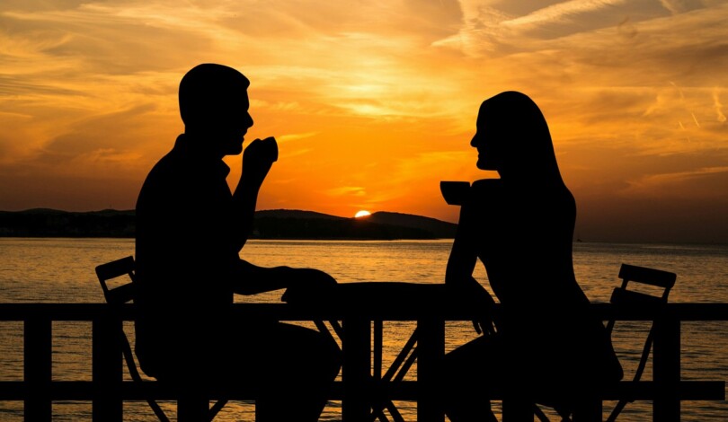 une homme et une femme qui partage un café sur une terrasse au bord de l’eau