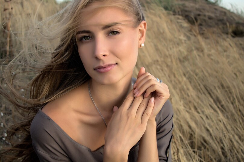 Une jolie femme blonde qui nous regardent assis dans une prairie