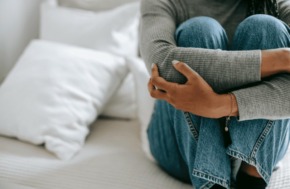 Une femme assise sur un lit qui se tient les genoux