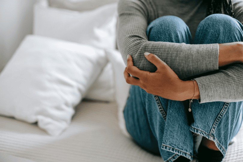 Une femme assise sur un lit qui se tient les genoux