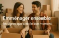 Photo d’un couple souriant assis parmi des cartons de déménagement, symbolisant l’emménagement ensemble et les signes que c’est le bon moment.