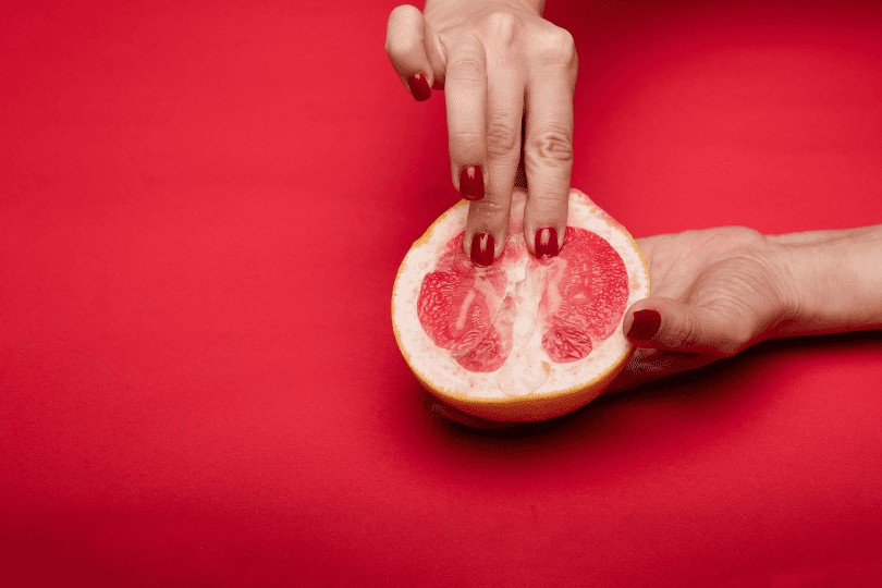 Deux doigts qui caresse l'intérieure d'une orange sanguine représentation afin de représenter le stimuli (masturbation féminine) sur les zone érogène du clitoris de la femme