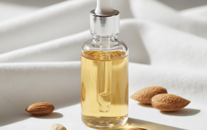 Huile d’amande douce bio dorée dans flacon transparent avec amandes fraîches, lubrifiant naturel pour peaux sensibles